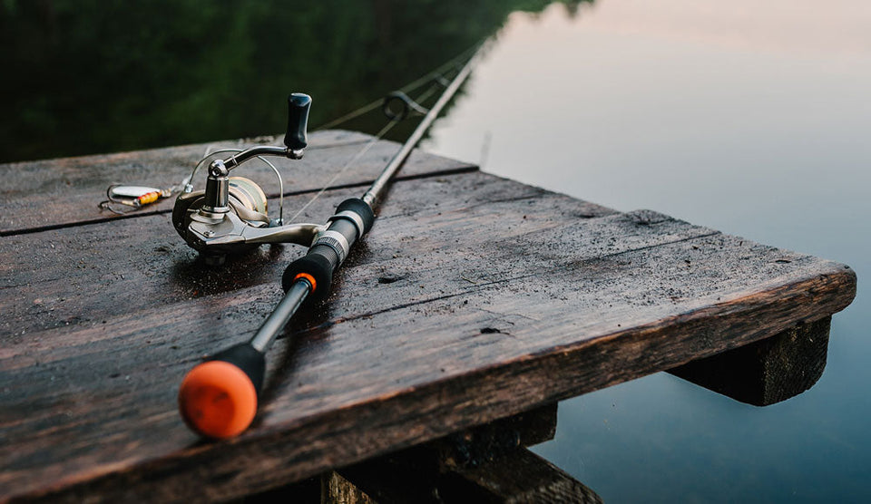 a fishing rod and reel on a wooden dock.	
