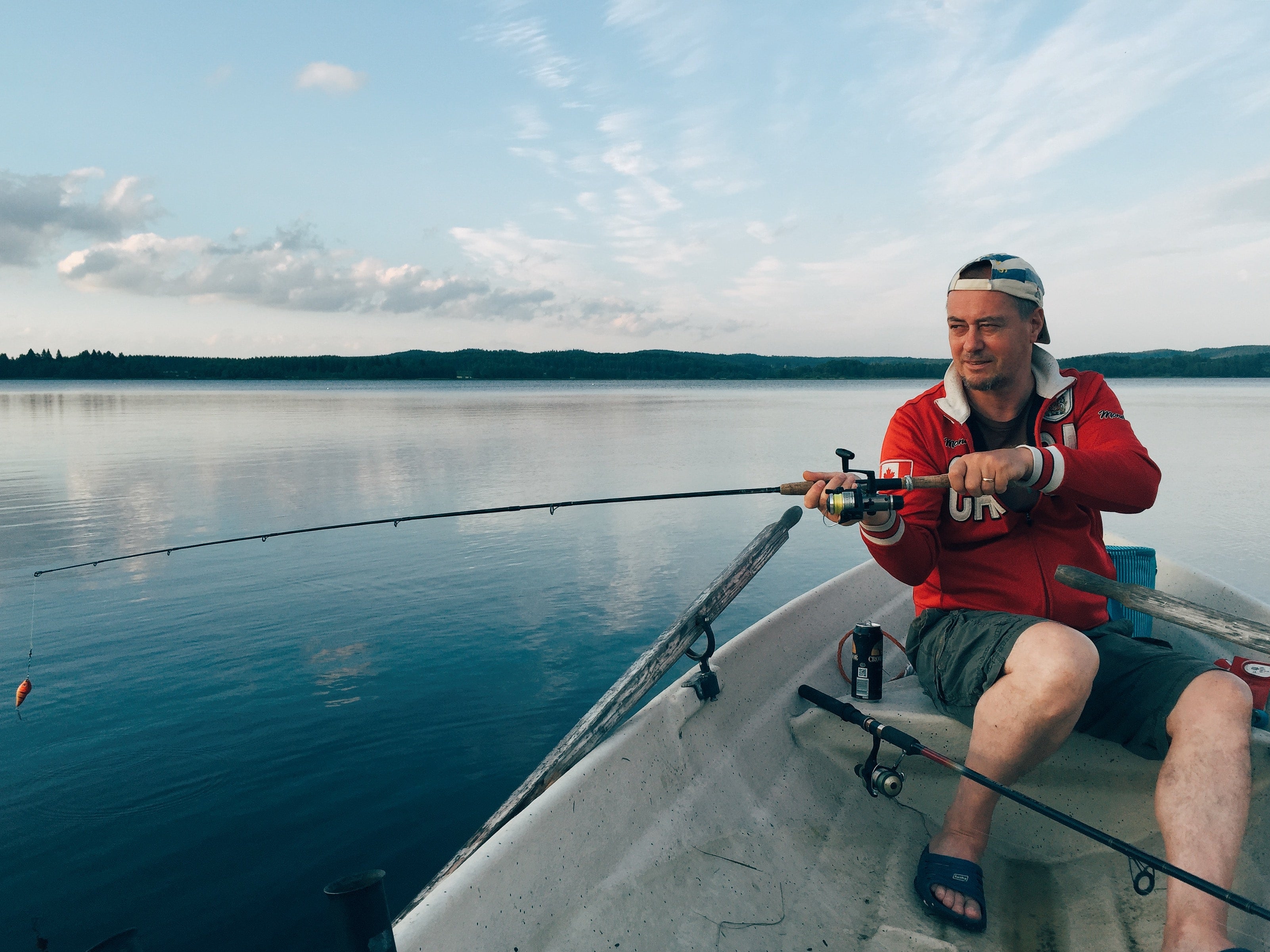 a man sitting in a boat holding a fishing rod.	